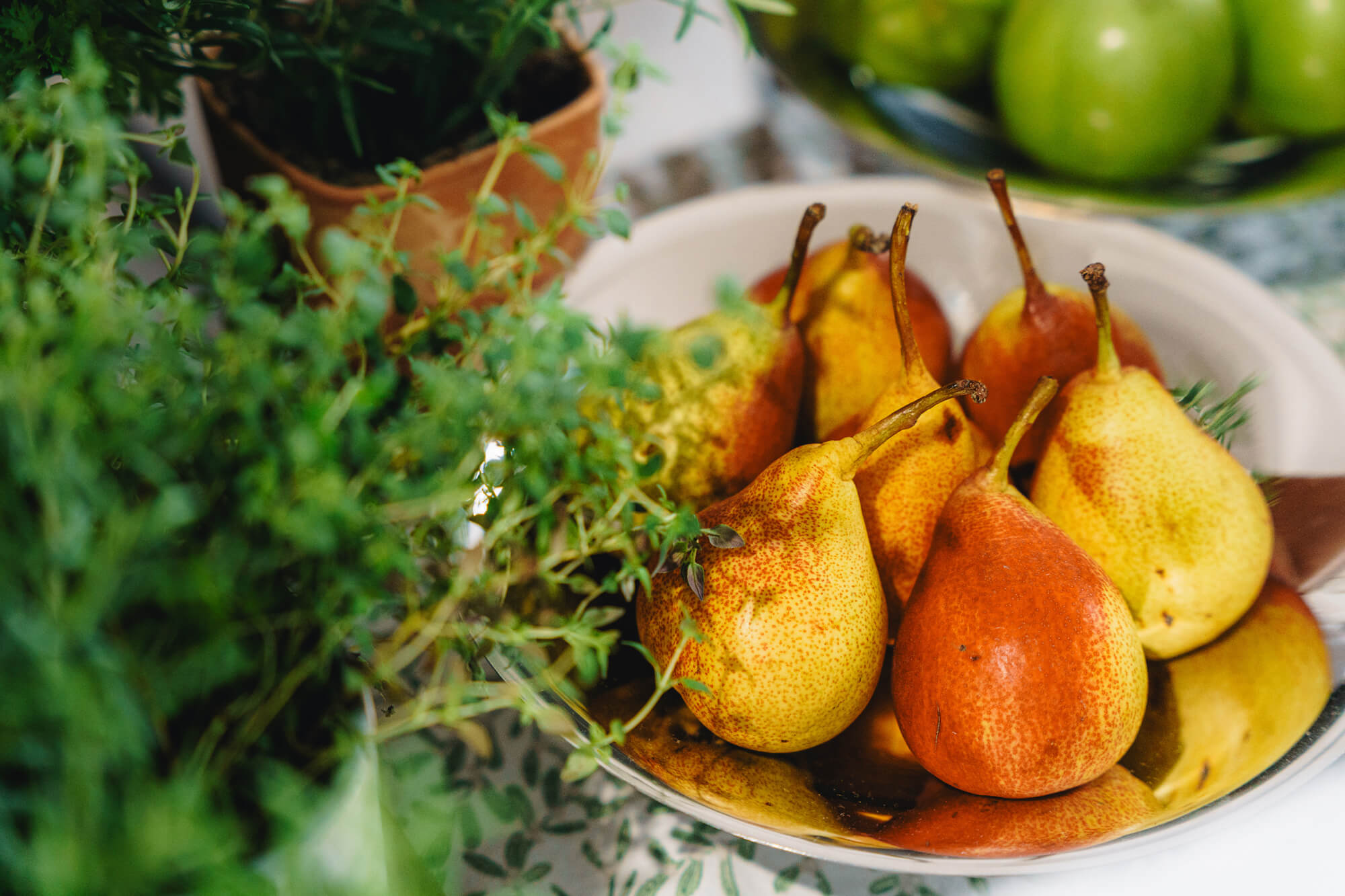 A bowl of ripe pears with fresh herbs